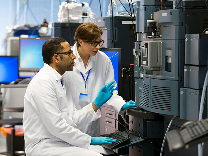 Scientists working with a Mass Spectrometer and recording the amount and type of chemicals present in a sample