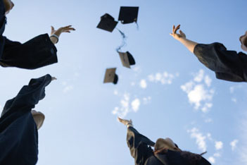 Students in graduation gowns tossing their hats into the air