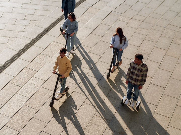 Aerial view of group of interracial millennials riding electric scooters and hoverboards having fun.