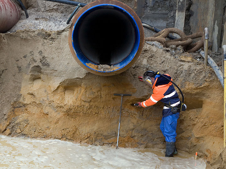 Engineer in person protective equipment collecting soil samples for environmental research