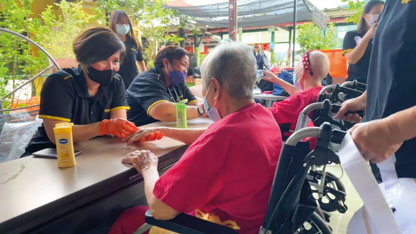 Elderly woman in wheelchair receiving aid from volunteer