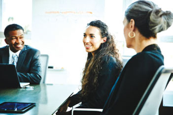 Formally dressed woman smiling at a meeting with colleagues