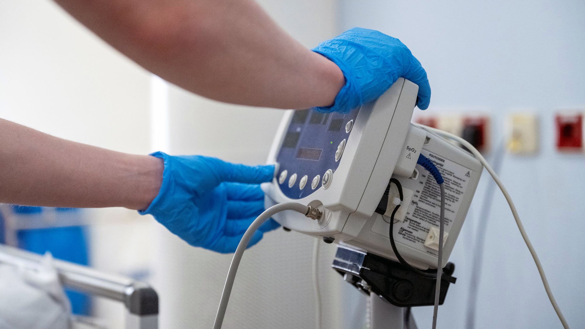 Close up view of a Healthcare professional operating a medical device while wearing blue protective gloves